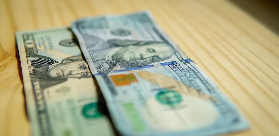 United States banknotes resting on a wooden counter